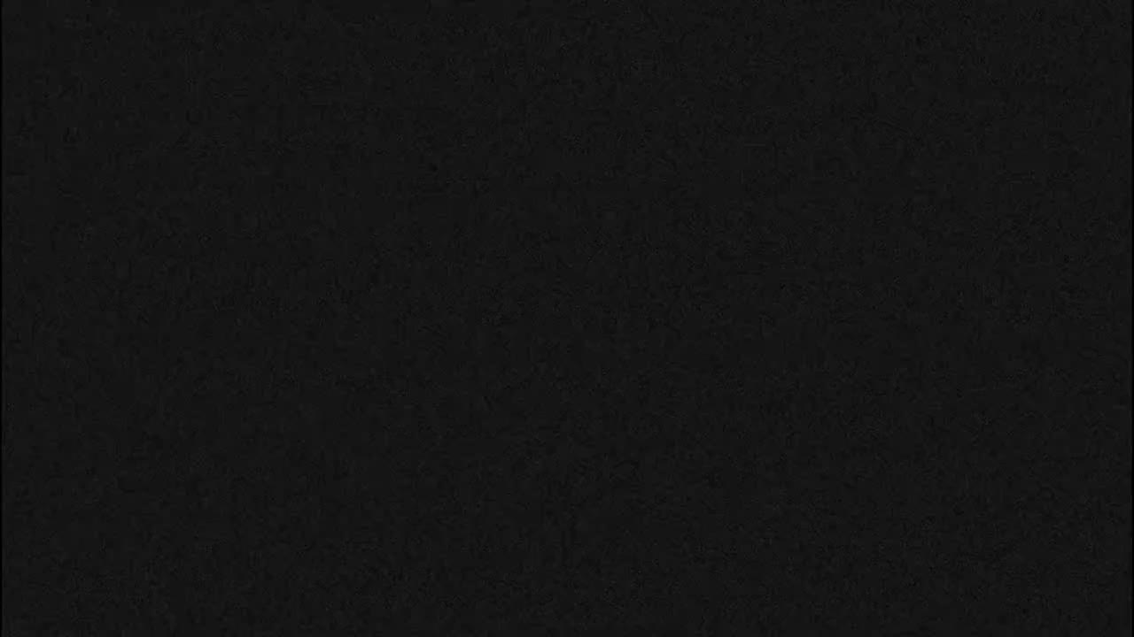 The image displays a dark, almost entirely black surface with a subtle, fine grainy texture.