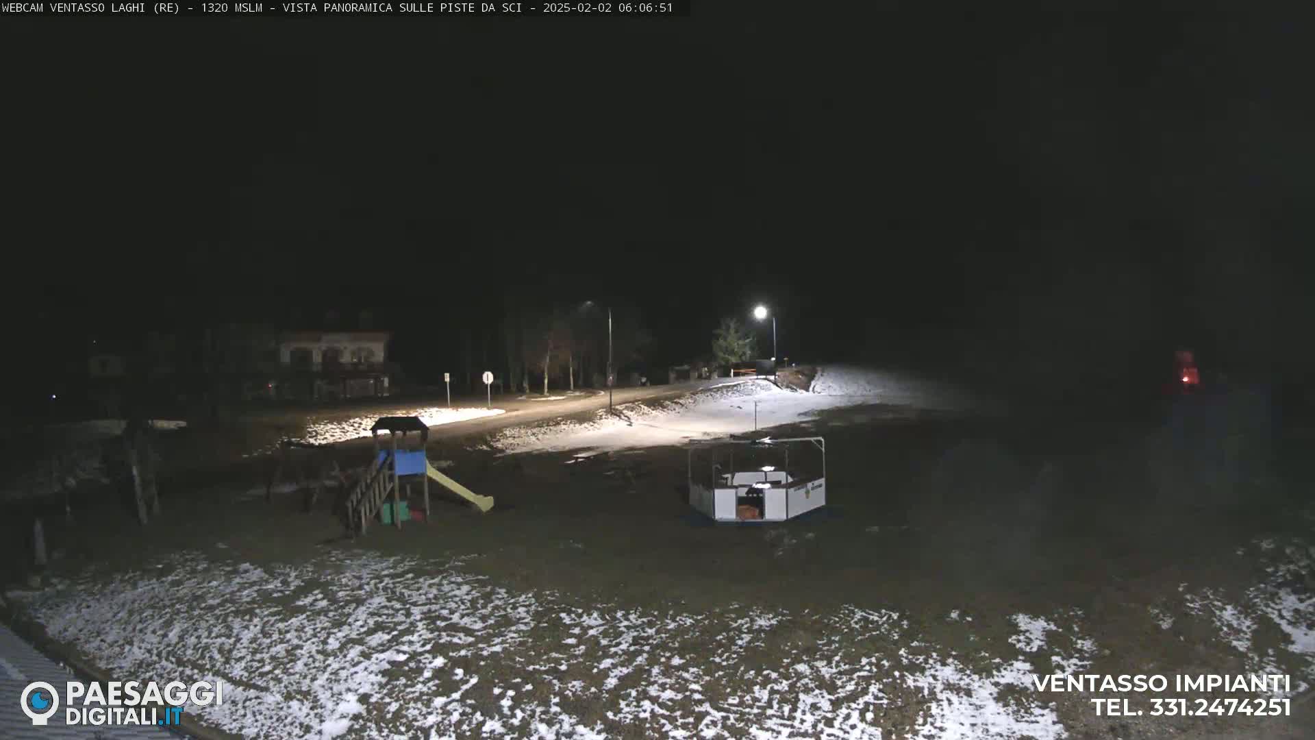 A snow-dusted playground and a small structure are visible at night under artificial light.