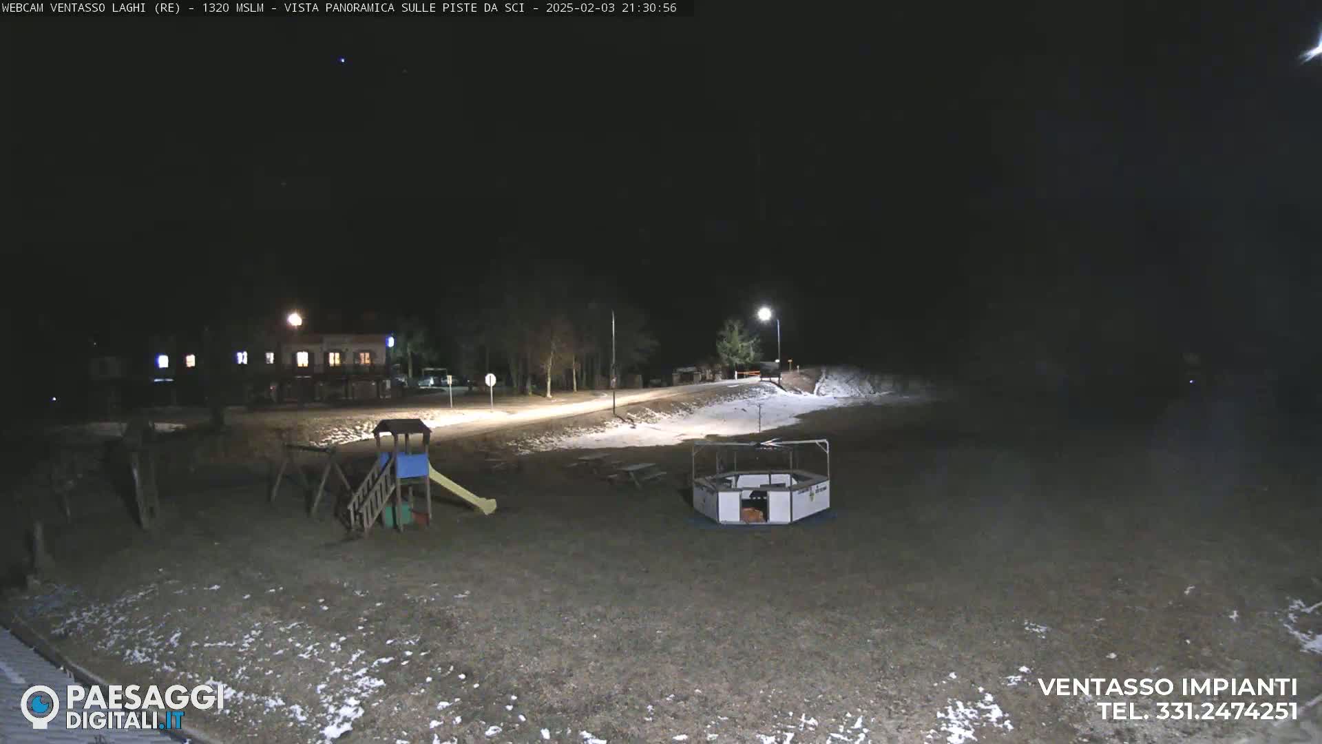 A playground with a slide and a merry-go-round is visible in a snow-dusted area at night, under a clear, dark sky.