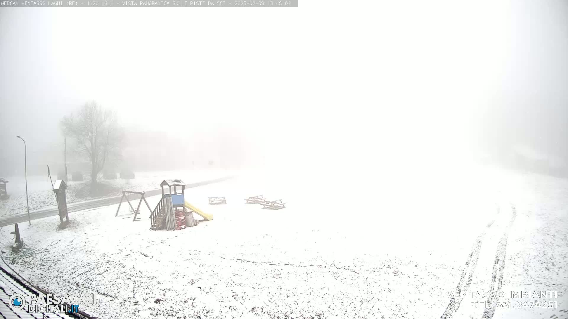 A snow-covered playground with picnic tables is visible through a thick fog.