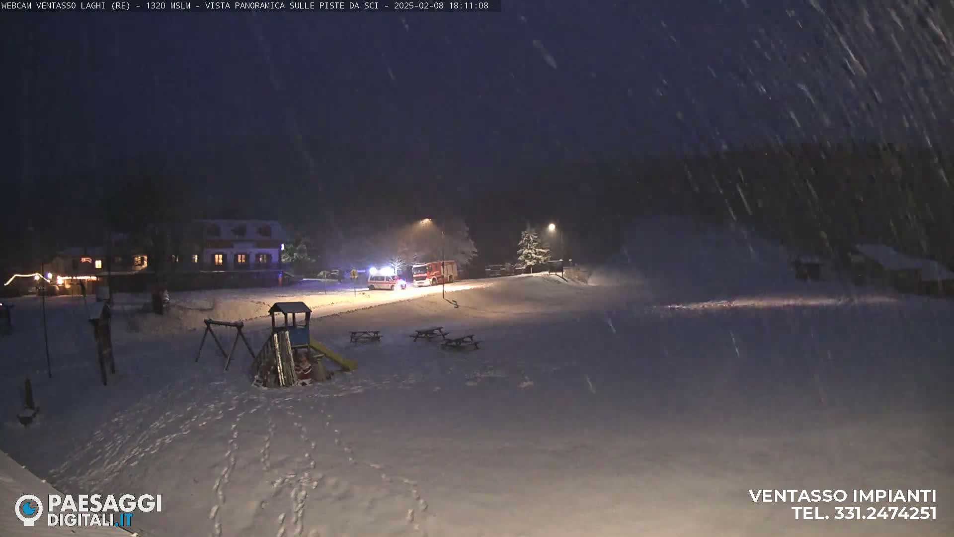A snow-covered playground and building are visible at night under heavy snowfall, with an ambulance and firetruck near the building.
