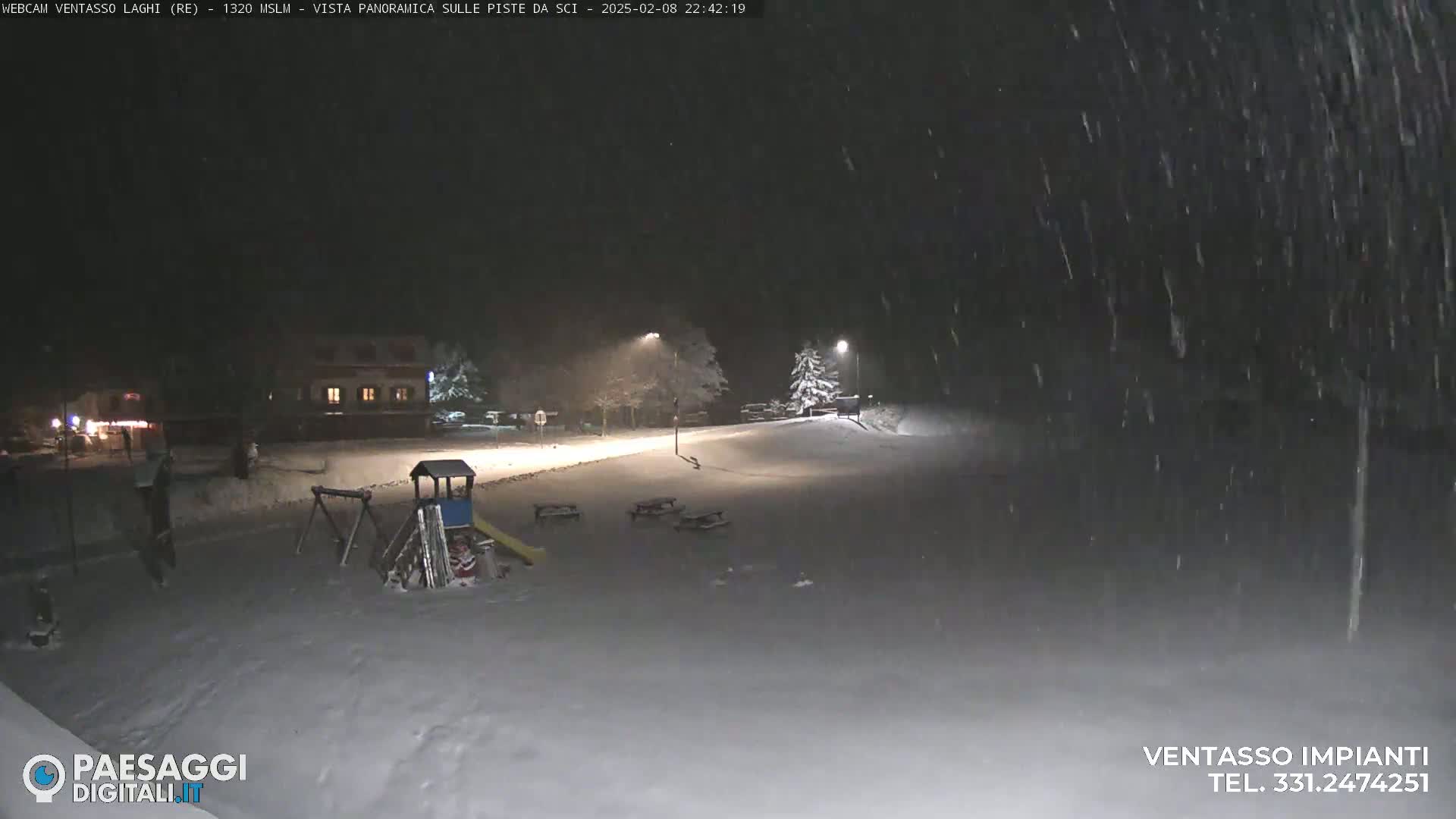 A snow-covered playground and a building are visible under heavy nighttime snowfall.