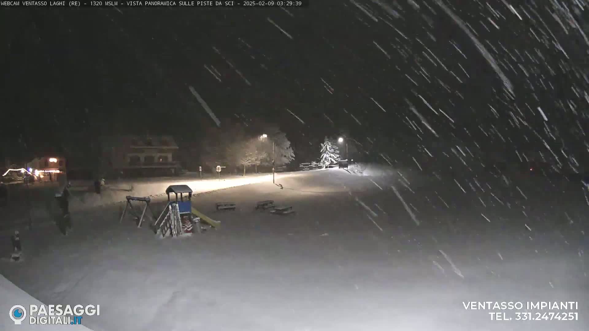 A snow-covered playground and a street scene are visible at night under heavy snowfall.