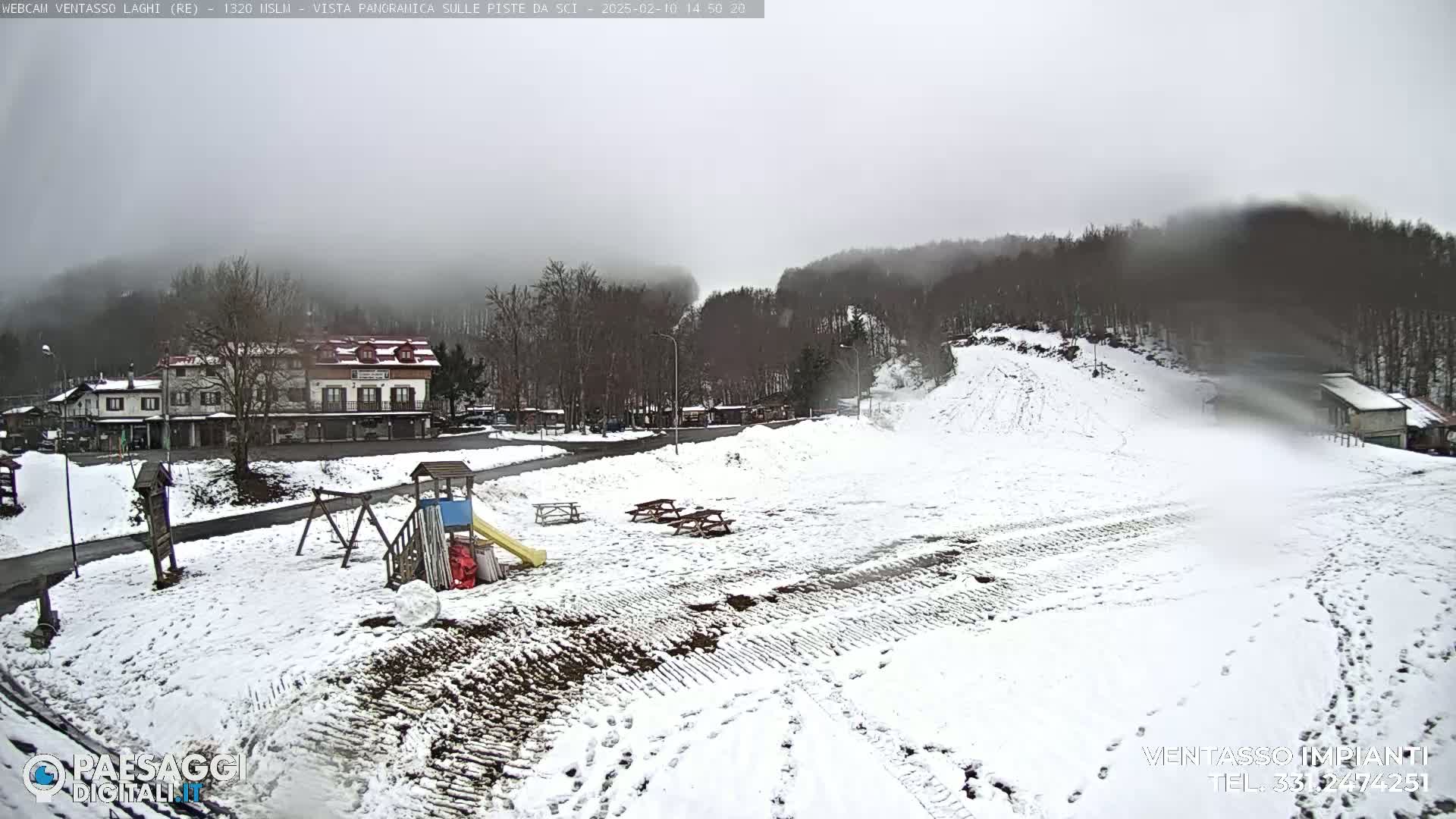 A snow-covered landscape with a building, playground, and picnic tables is visible under a foggy sky.