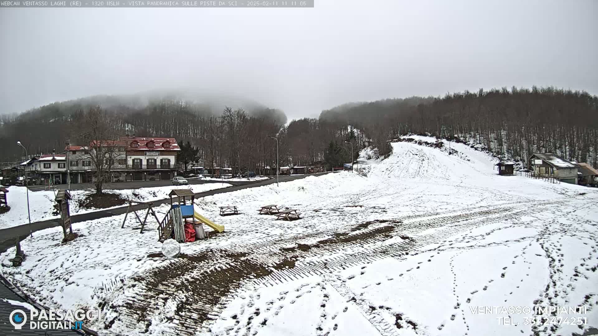 A snow-covered playground and ski slope are visible beneath an overcast sky, with buildings and trees in the background.