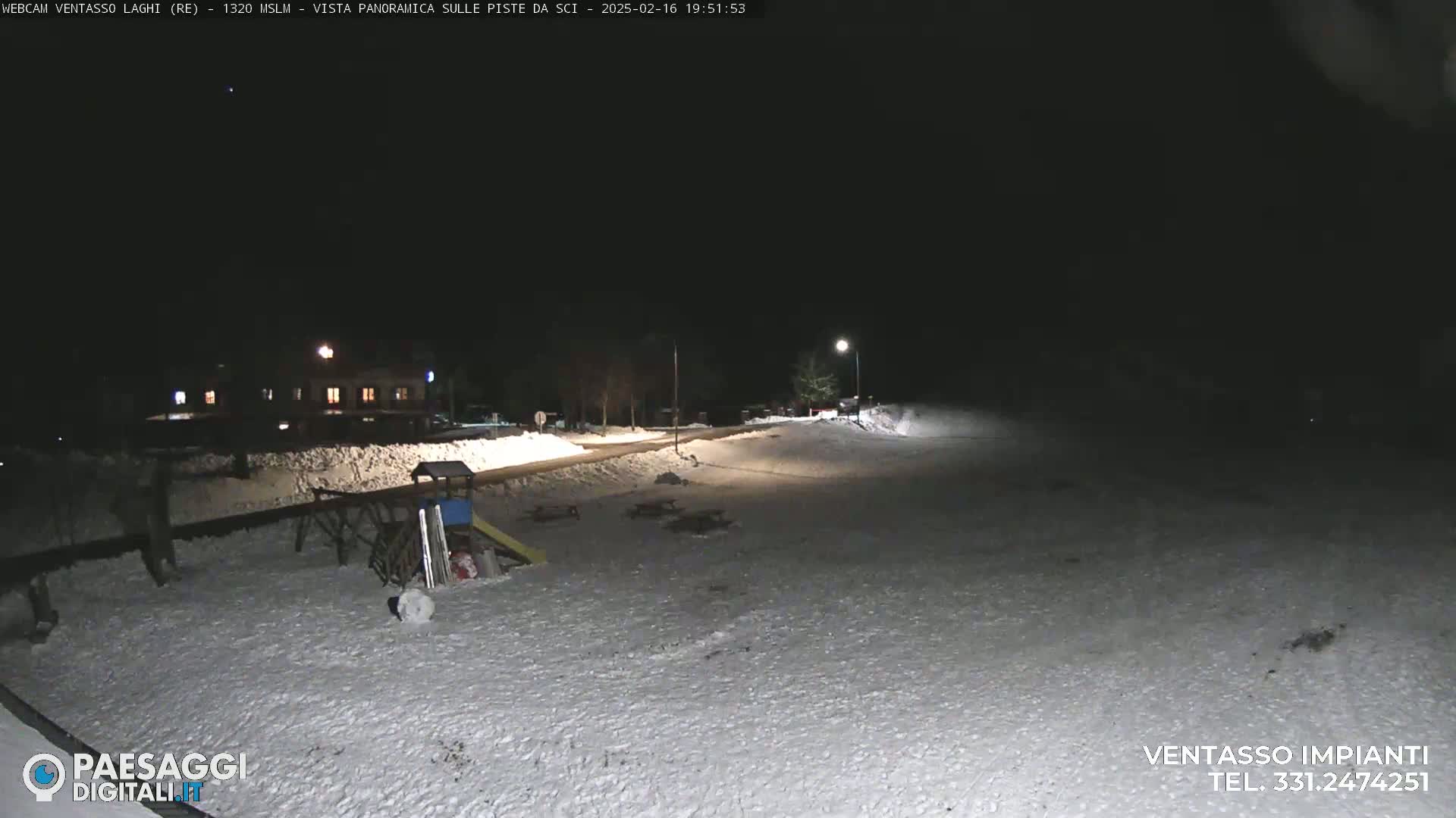 A snow-covered playground and a building are visible at night, illuminated by streetlights.