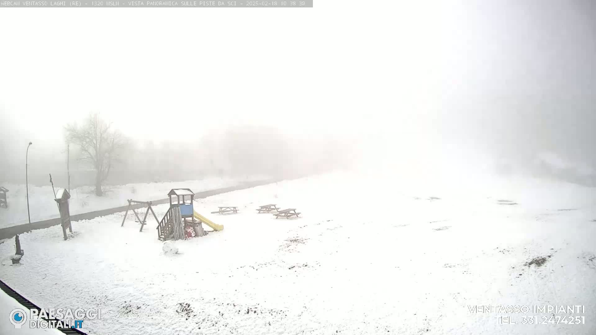 A snow-covered playground with a slide and swings is visible in a foggy, snowy landscape.