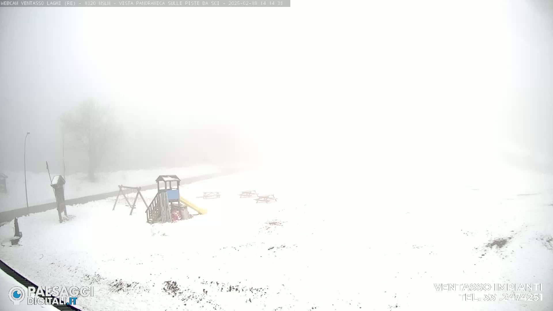A snow-covered playground with a slide and swing set is visible in a dense fog.