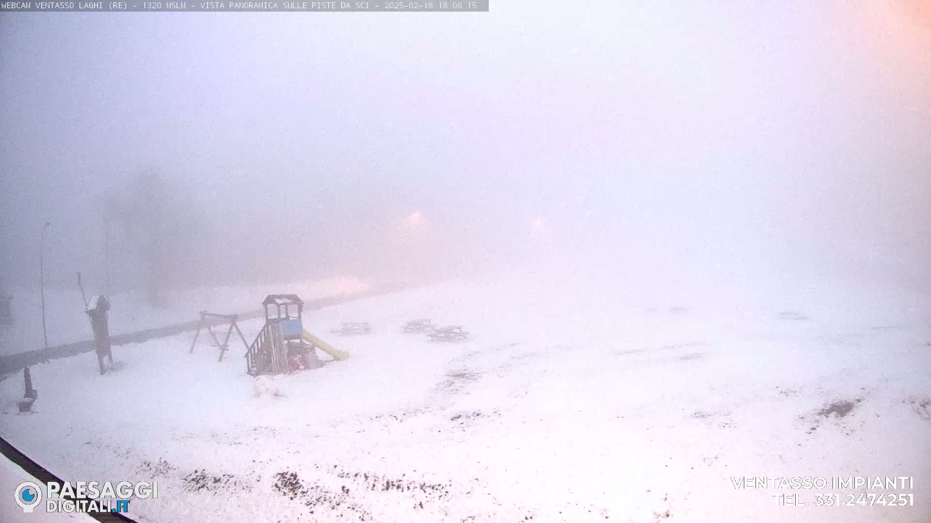 A snow-covered playground and picnic tables are barely visible through heavy fog.