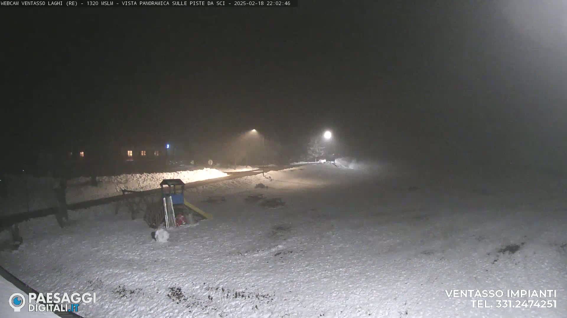 A snow-covered playground area is dimly lit at night under foggy conditions.