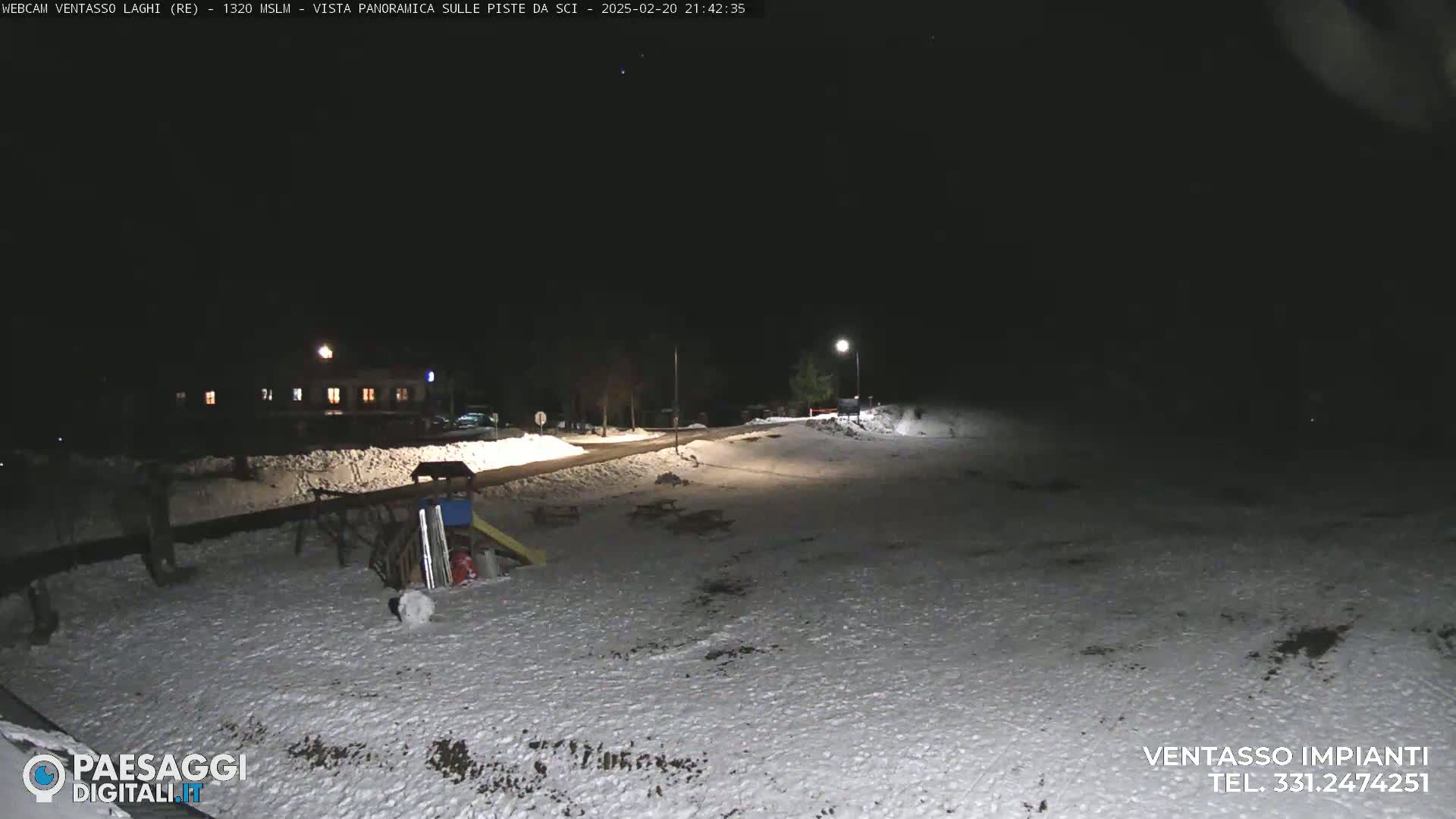 A snow-covered playground and a building are visible at night under a dark sky.