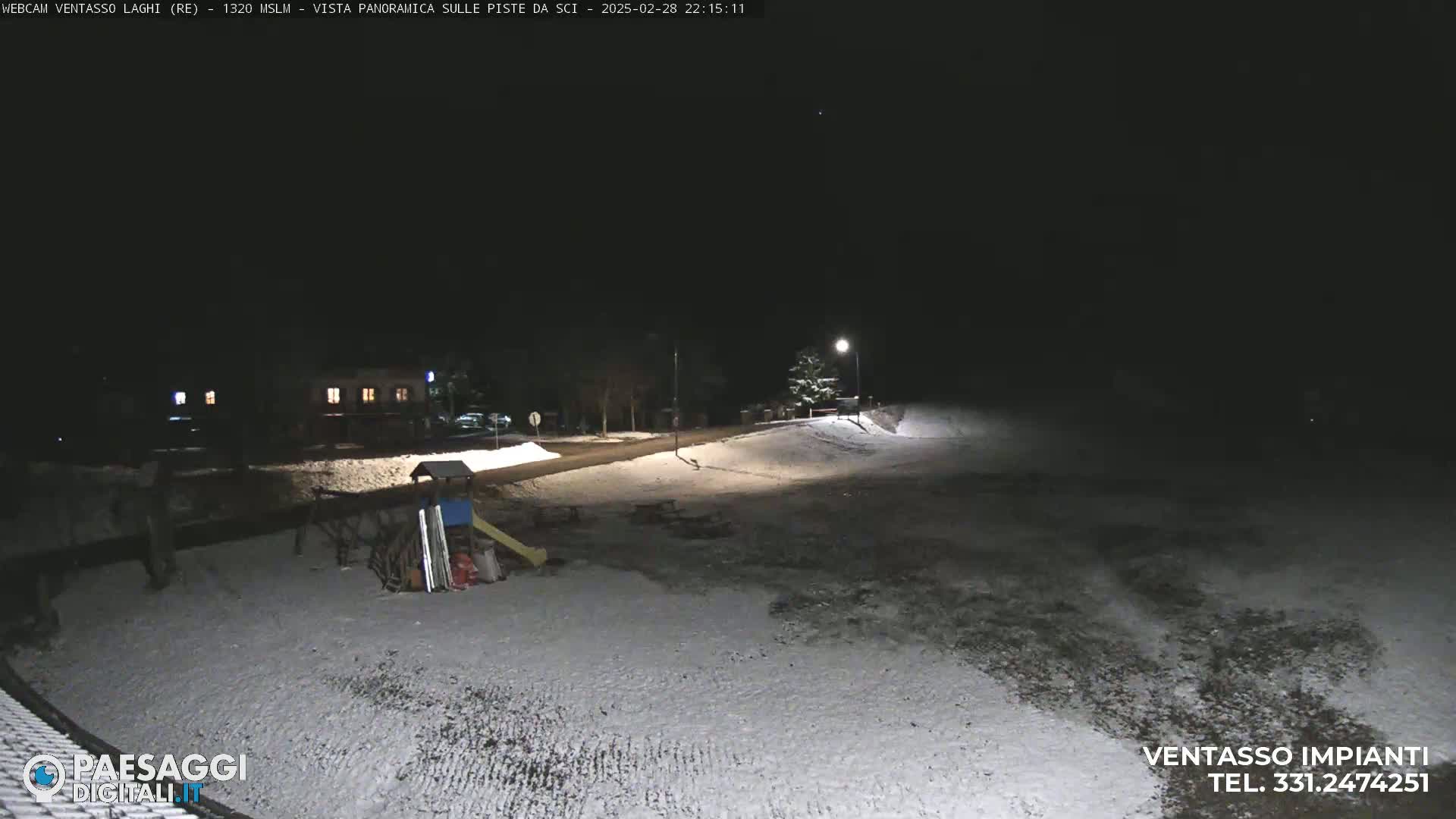 A snow-covered playground and road are visible at night under a clear, dark sky.