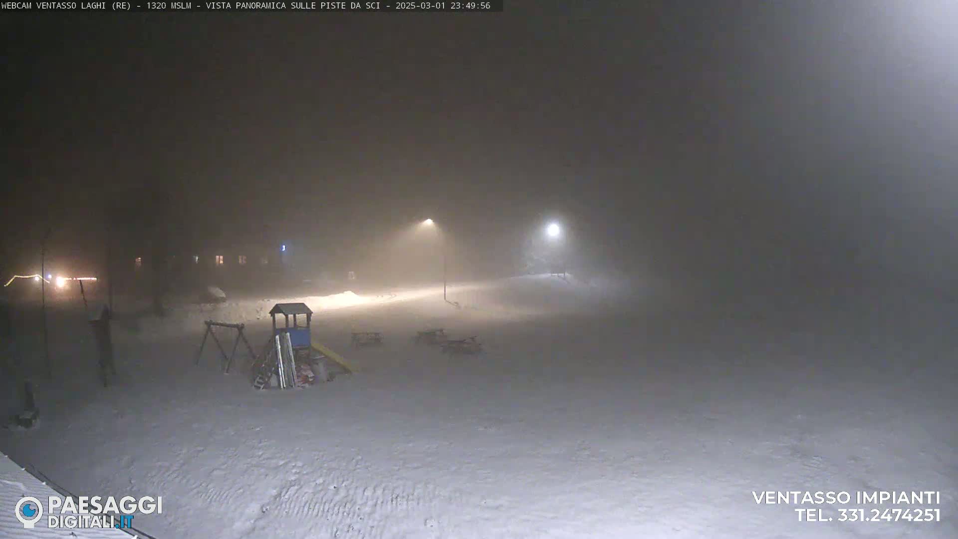 A snow-covered playground and empty picnic tables are visible under heavy snowfall at night, illuminated by dim streetlights.