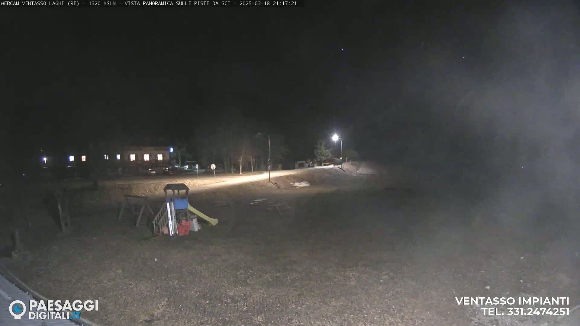 A nighttime view of a playground and a building under a dark, clear sky.
