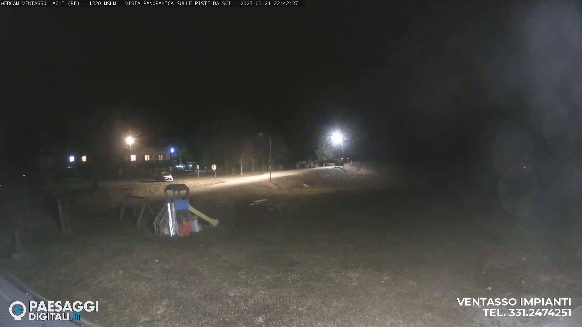 A nighttime, dimly lit outdoor scene shows a playground, a road, and a building in the distance.