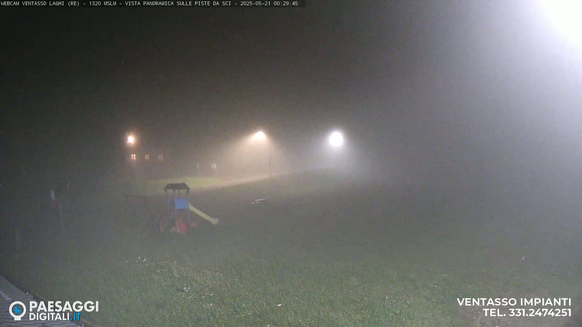 A playground with a slide is visible in the foggy night, illuminated by distant lights.