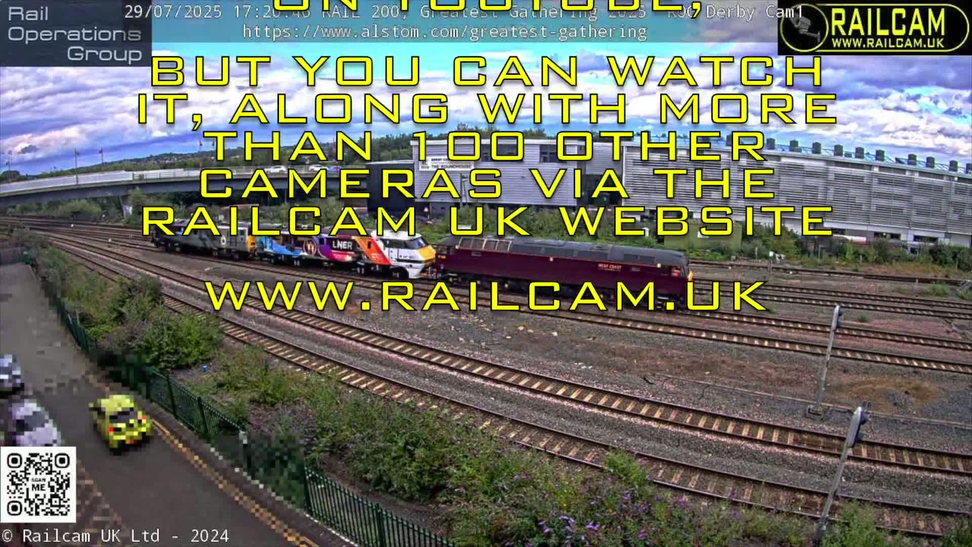 Three trains are visible on a railway track under a partly cloudy sky.