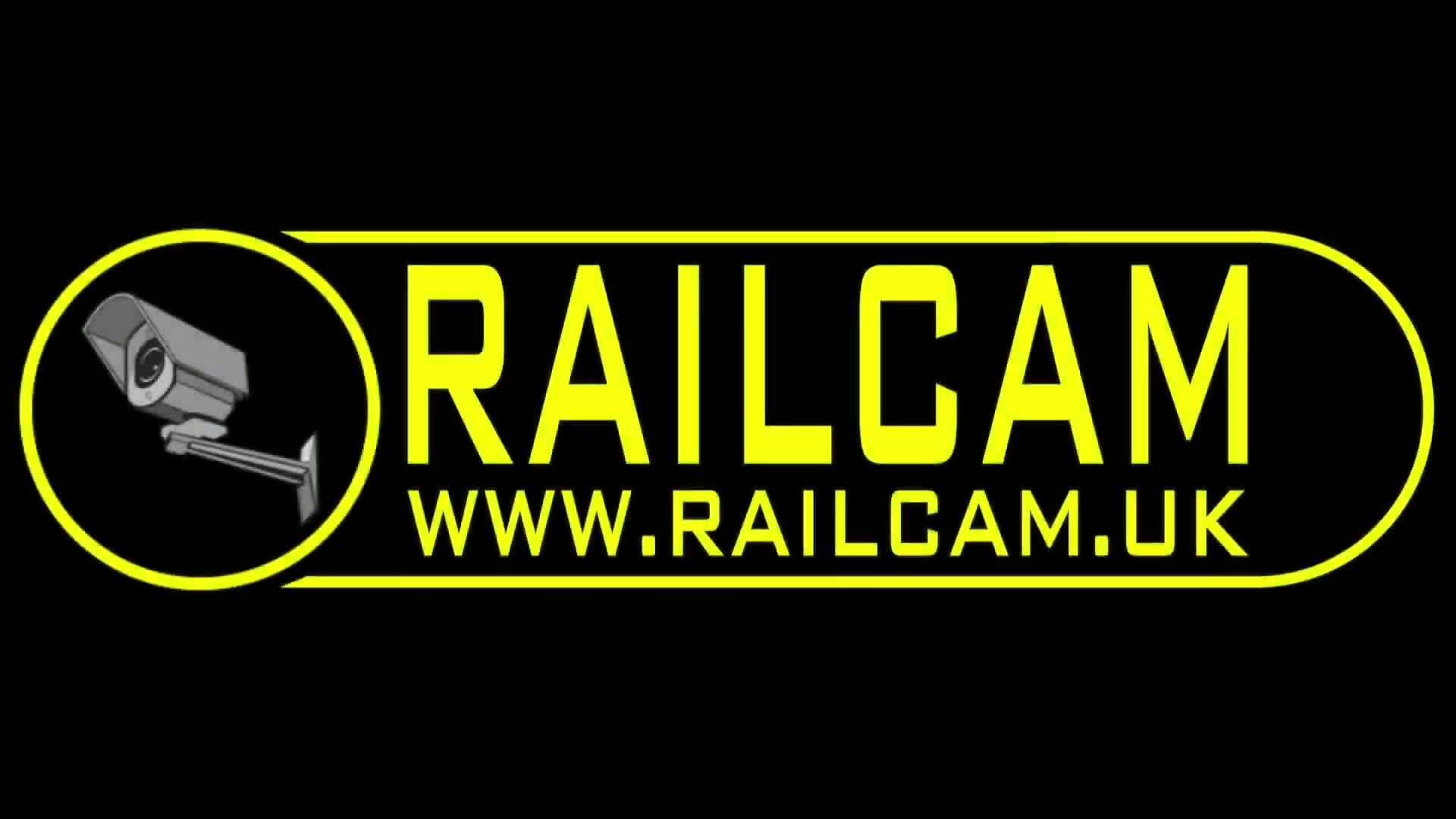 A security camera is depicted to the left of the word RAILCAM in bright yellow lettering on a black background.