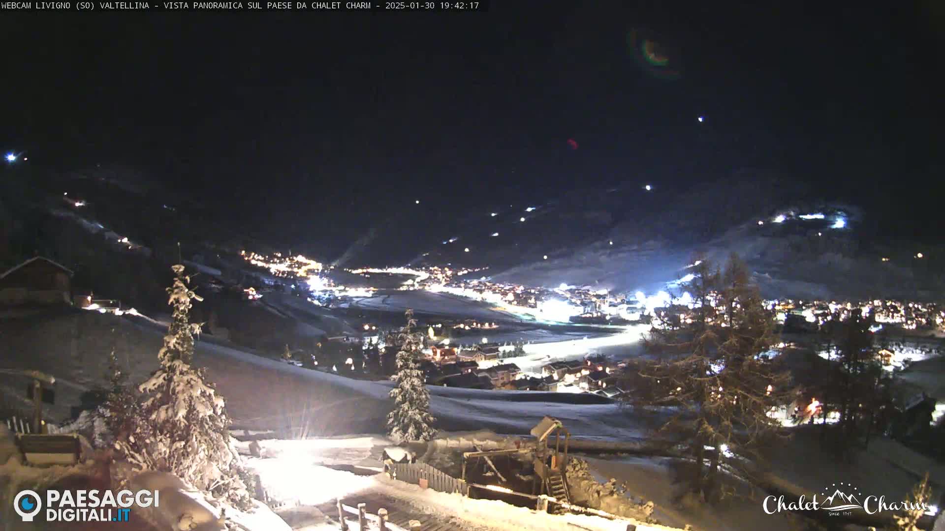 A snow-covered mountain village is illuminated at night under a clear, dark sky.