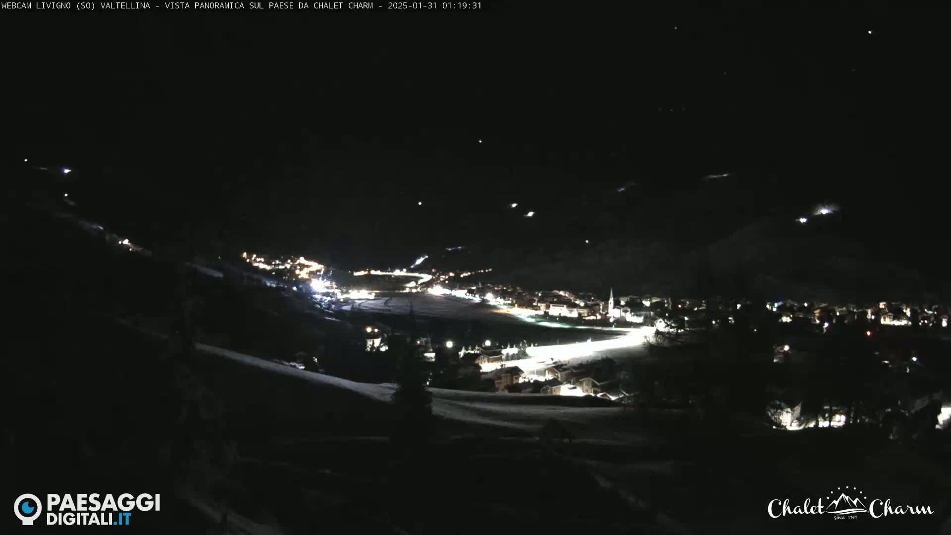 A nighttime, panoramic view of a snow-covered town illuminated by lights under a clear, dark sky.