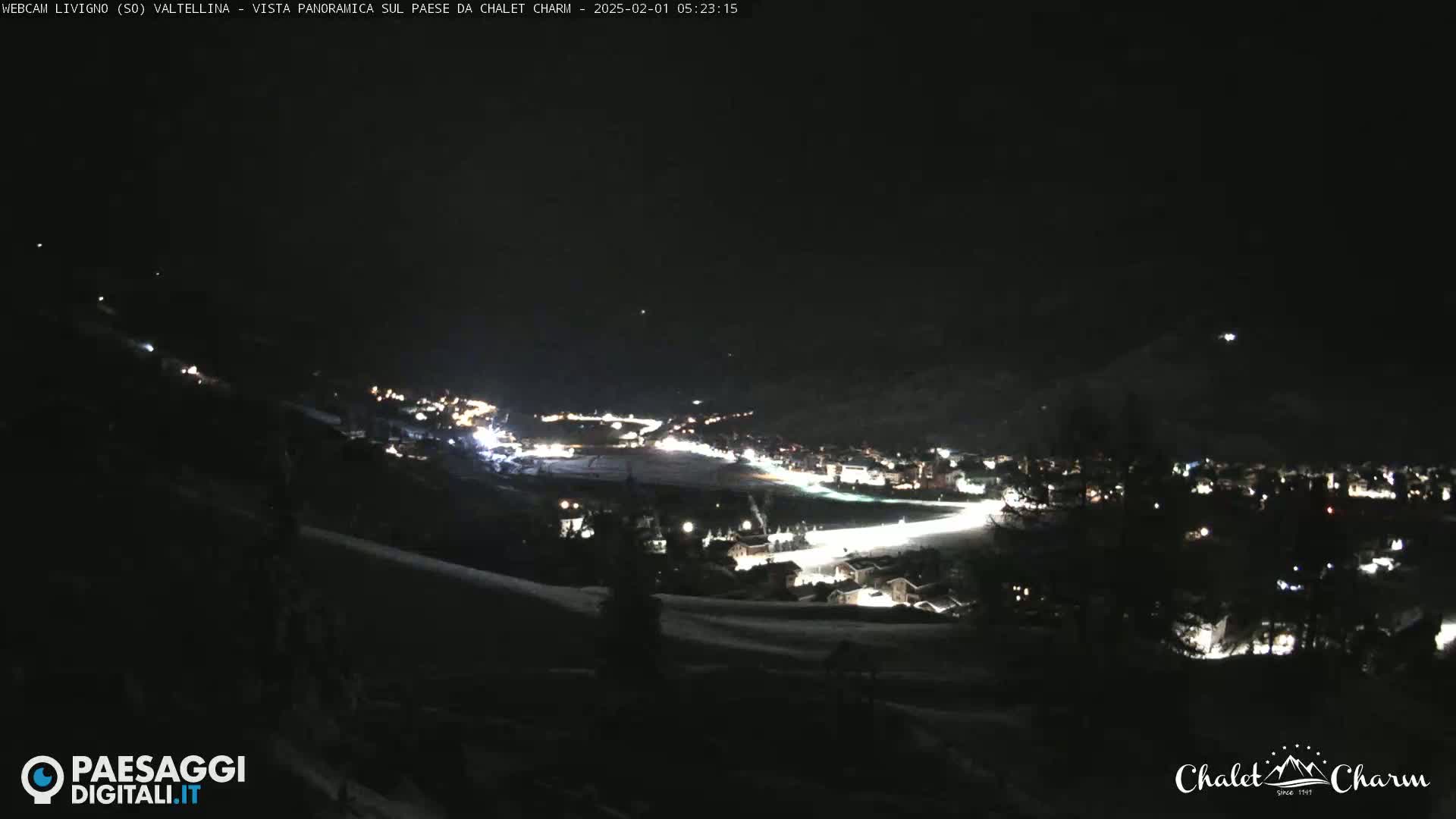 A nighttime, panoramic view of a snow-covered town illuminated by scattered lights.