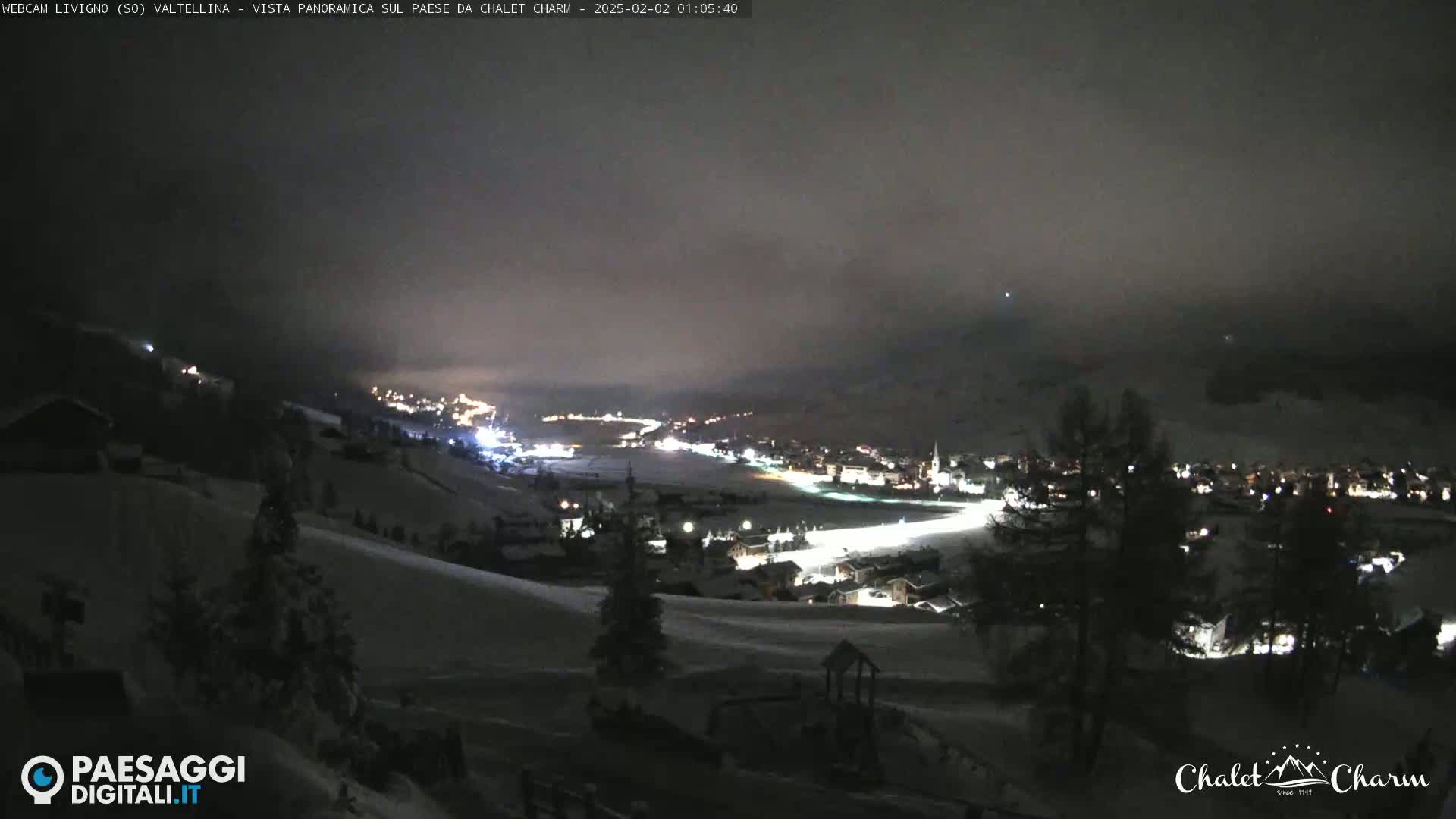 A snow-covered town is illuminated at night under a dark, cloudy sky.