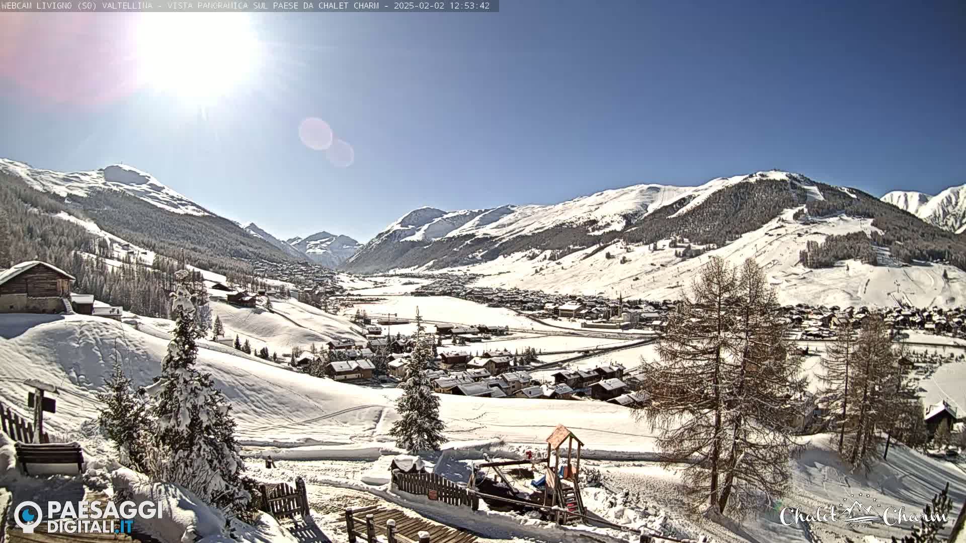 A snow-covered mountain village is viewed from a hillside on a sunny winter day.