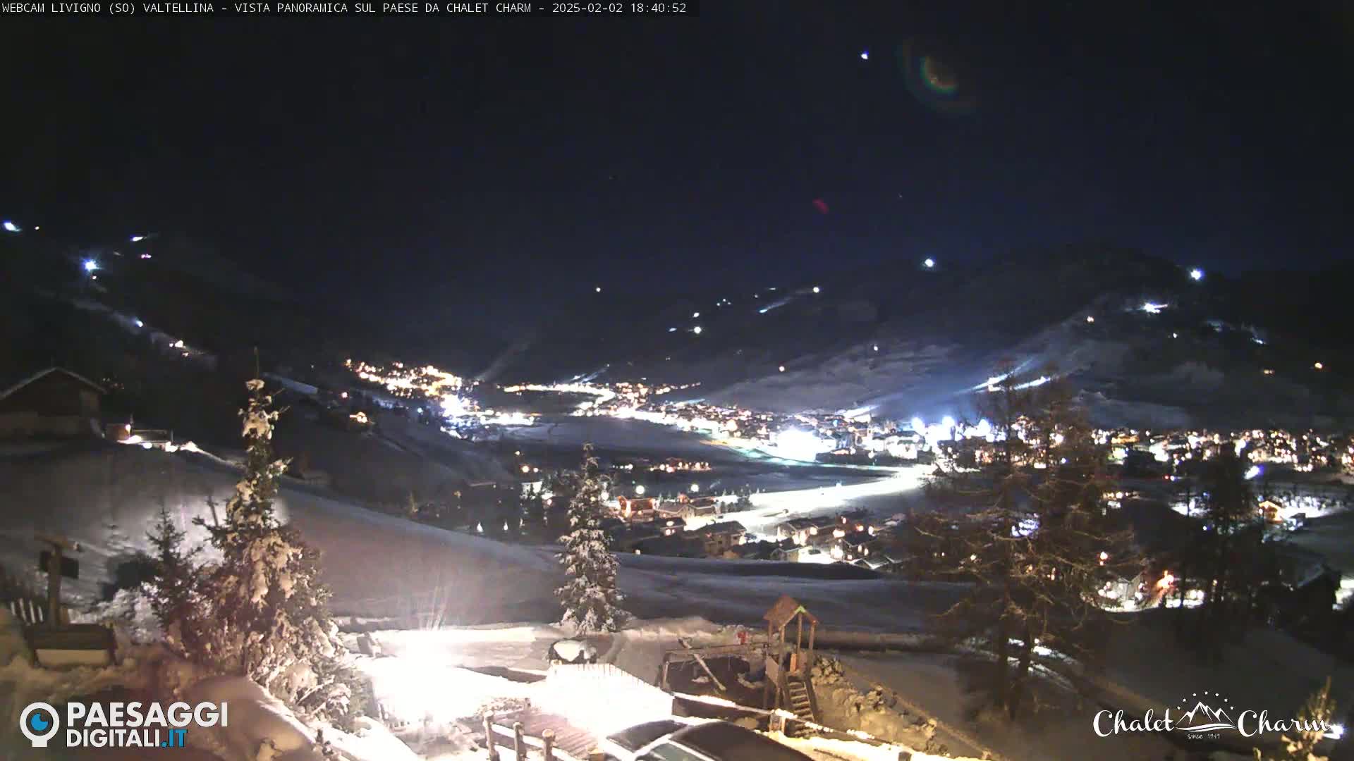 A nighttime, panoramic view of a snow-covered town nestled in a valley under a dark, clear sky.