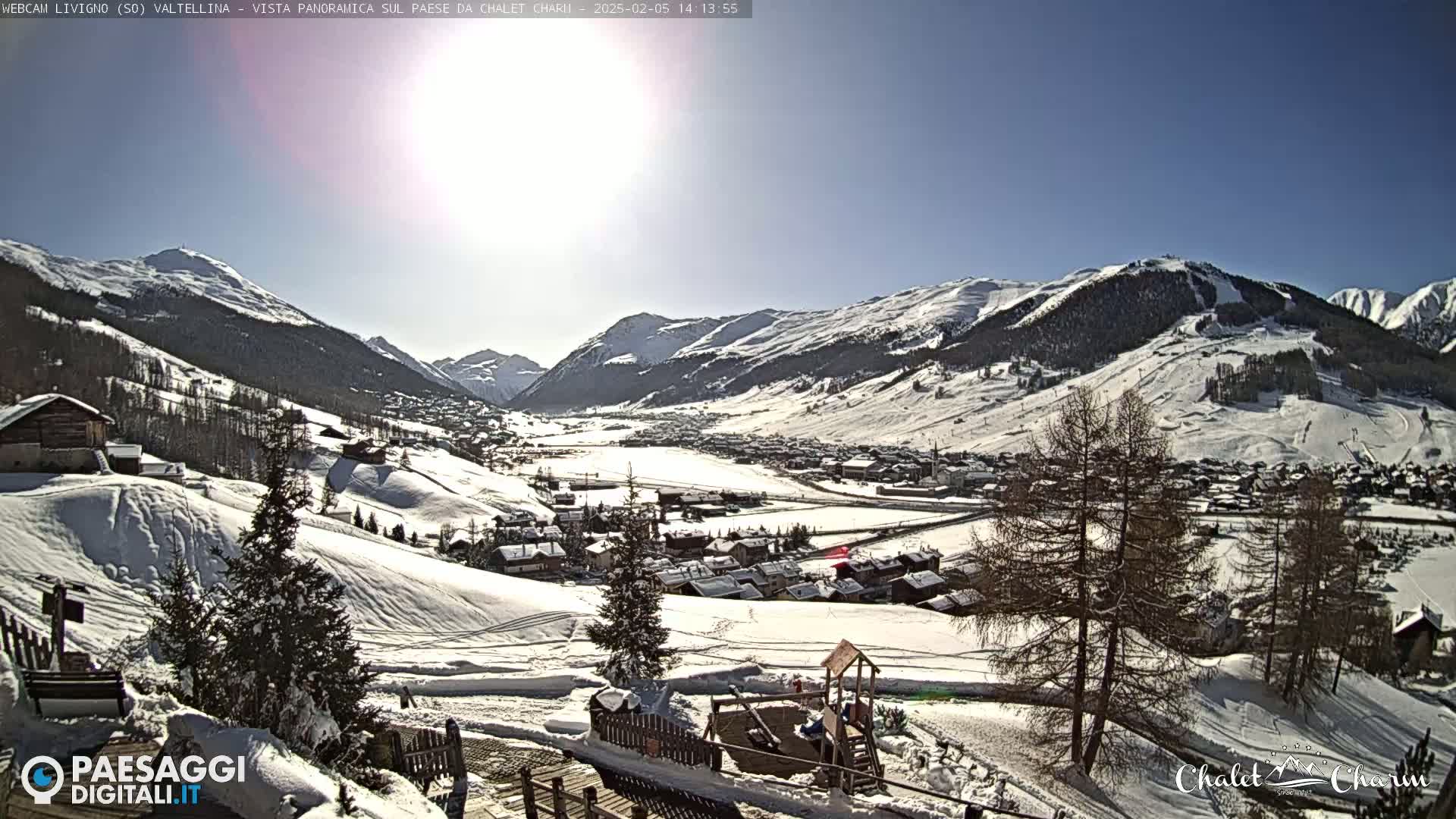 A snow-covered mountain valley town is viewed from a hillside on a sunny day.