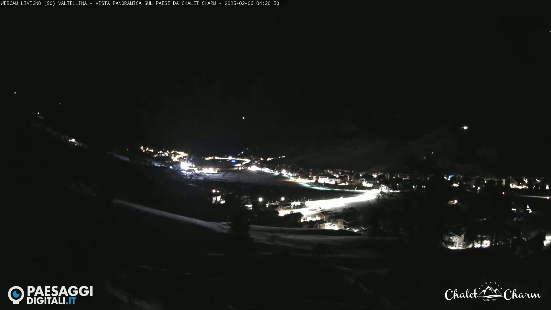 A nighttime, panoramic view of a snow-covered town illuminated by scattered lights.