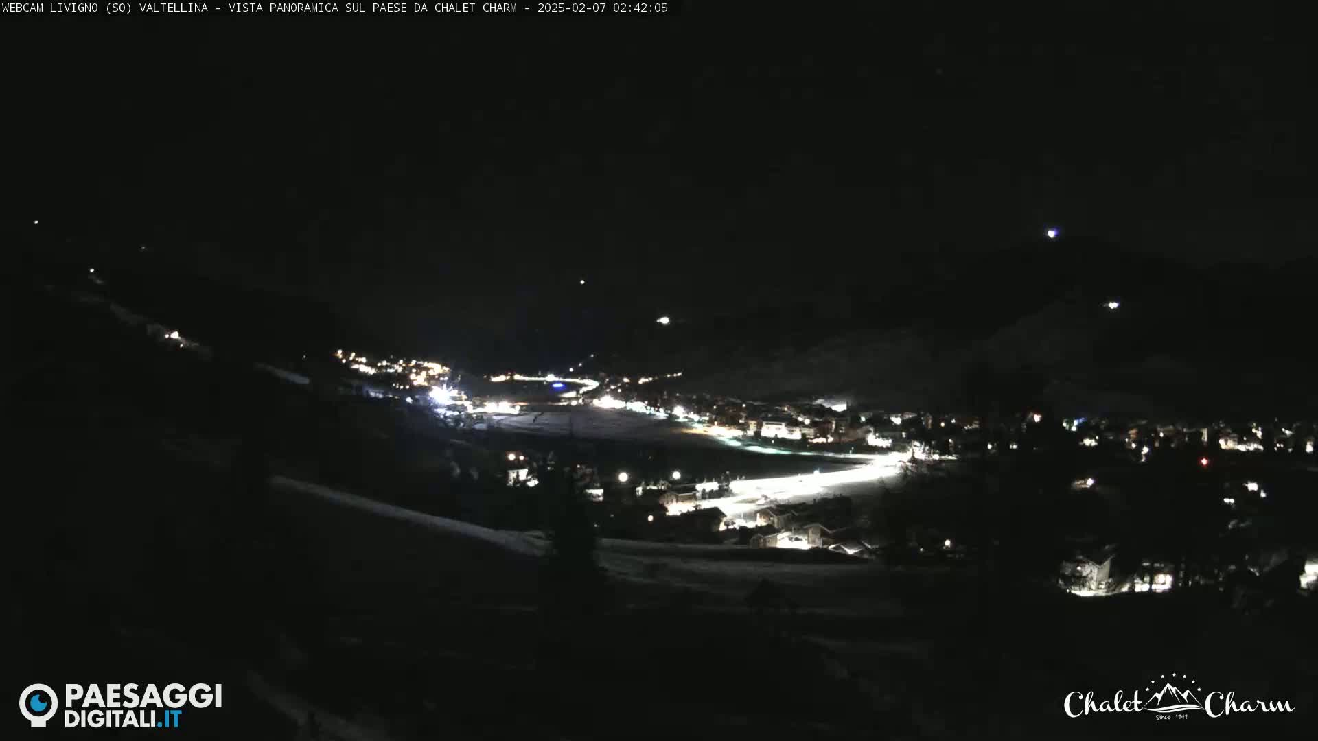 A nighttime, panoramic view of a snow-covered town illuminated by lights under a clear, dark sky.