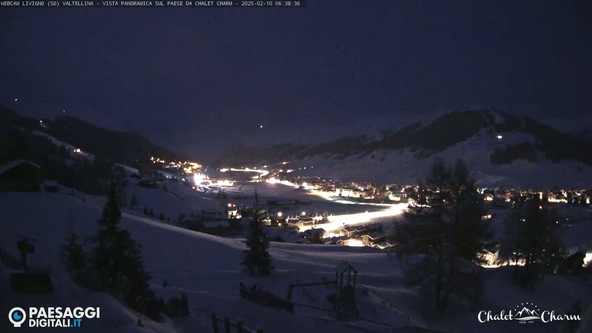 A snow-covered mountain village is illuminated at night under a dark sky.
