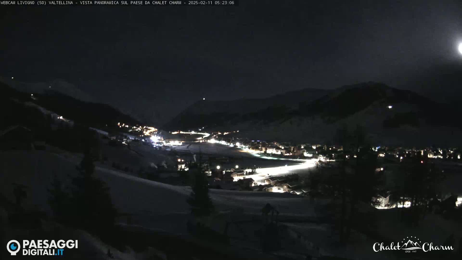 A moonlit, snow-covered mountain village is illuminated at night.