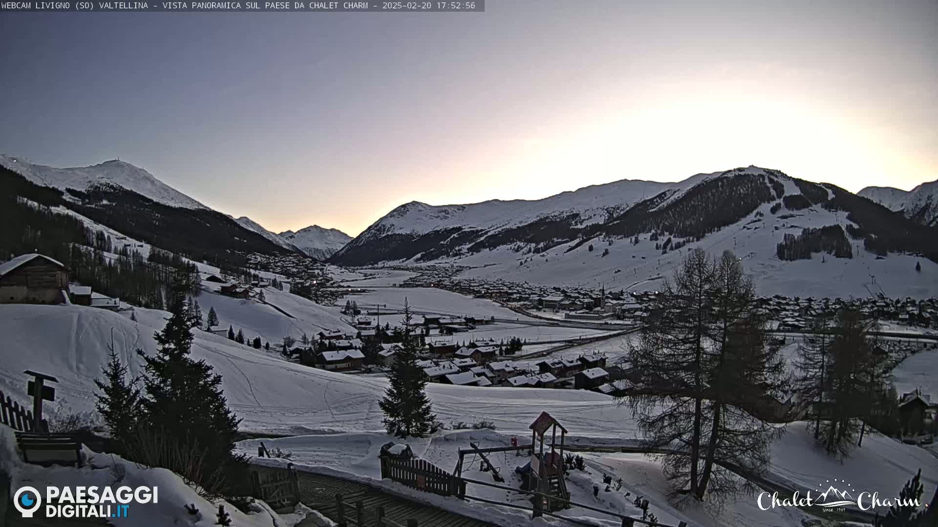 A snow-covered village nestled in a valley between snow-capped mountains at twilight.