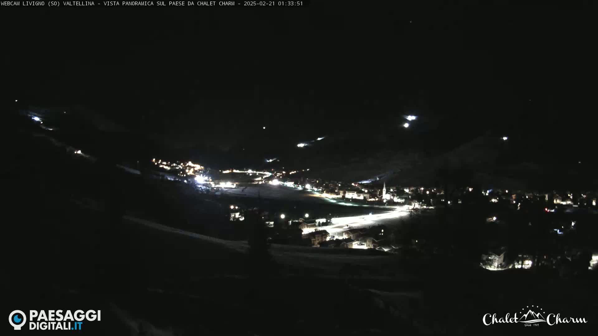 A nighttime, panoramic view of a snow-covered town illuminated by lights, under a clear, dark sky.