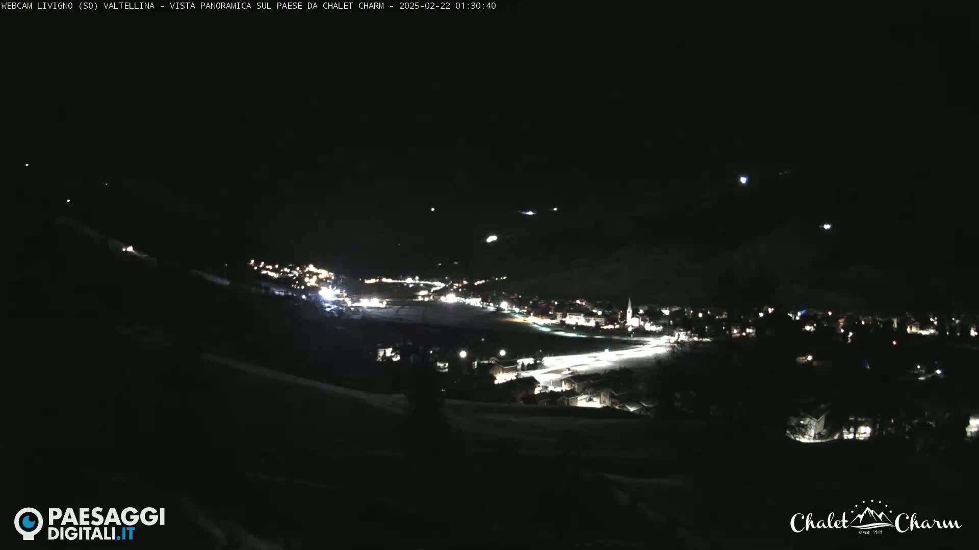 A nighttime panoramic view of a snow-covered town illuminated by streetlights.