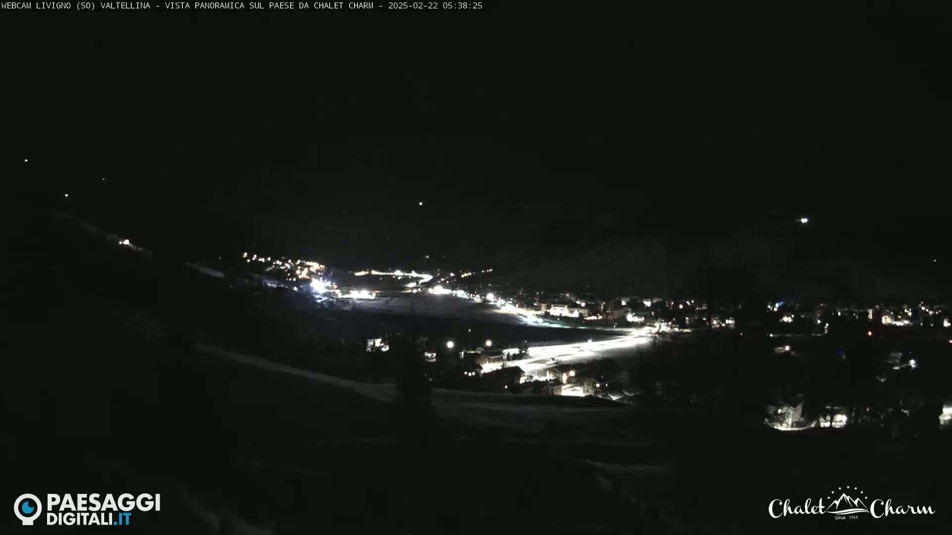 A nighttime, panoramic view of a snow-covered town illuminated by scattered lights.