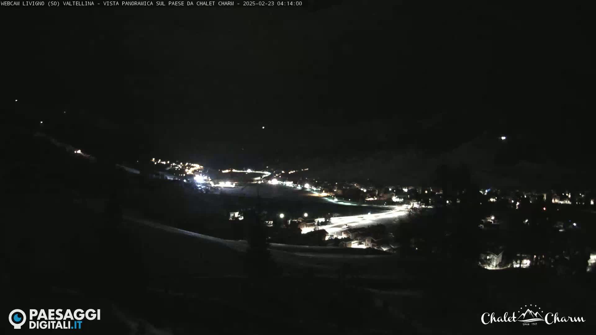 A nighttime, snowy, panoramic view of a town illuminated by scattered lights.