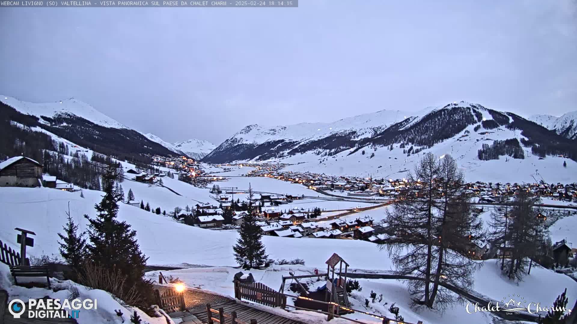 A snow-covered village nestled in a valley between snow-capped mountains at twilight.