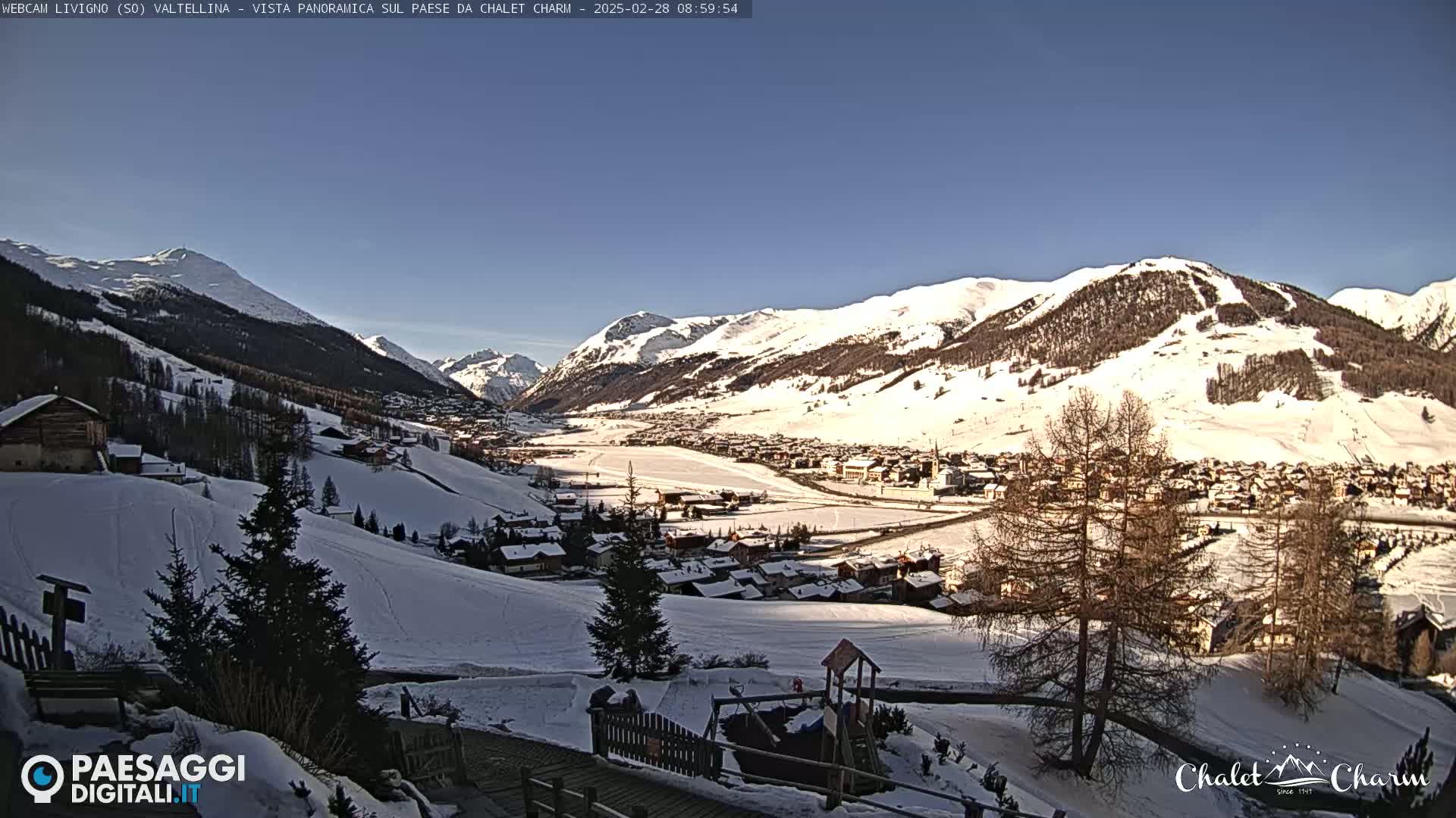 A snow-covered mountain village nestled in a valley under a clear blue sky.