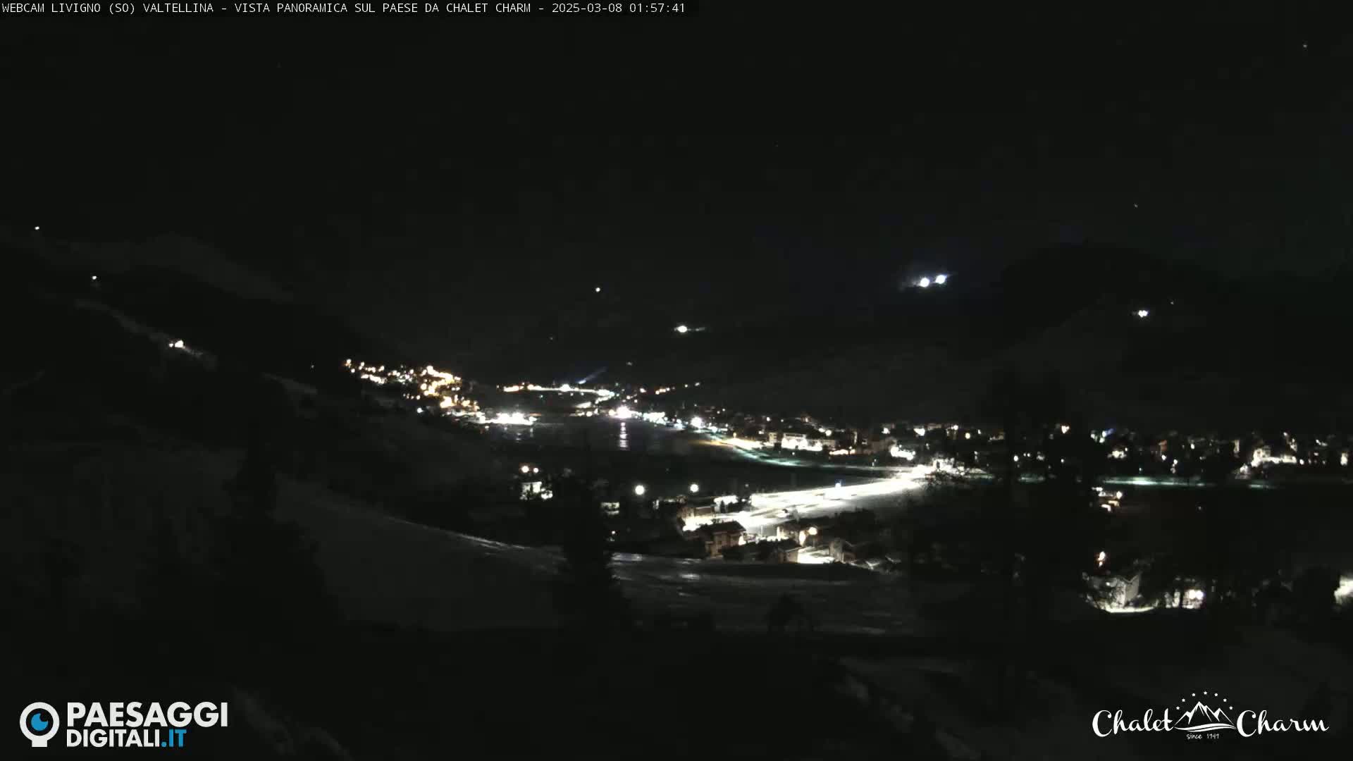 A nighttime, panoramic view of a snow-covered town illuminated by lights under a clear, dark sky.