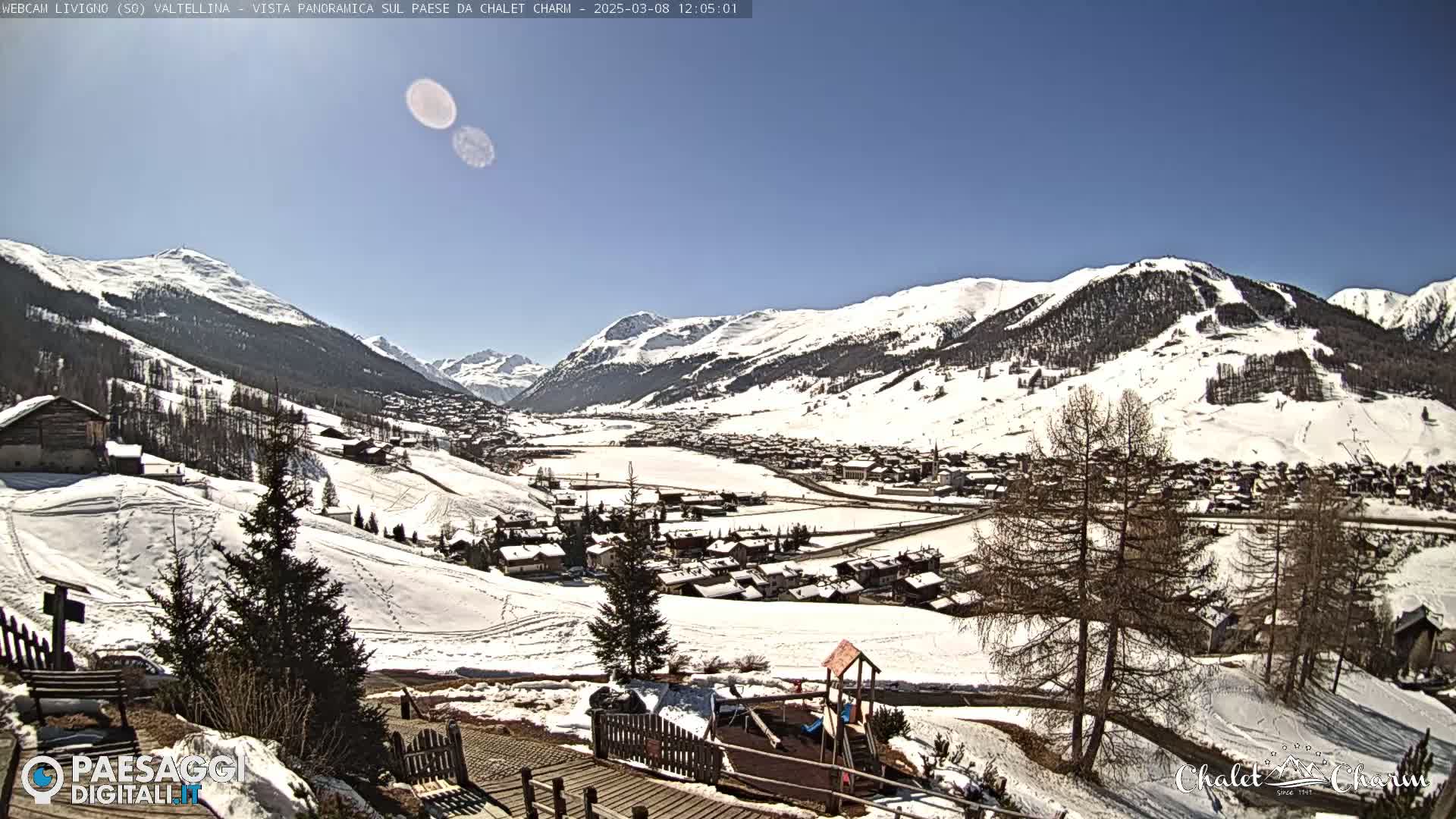 A snow-covered mountain village is seen from a high vantage point on a sunny day.