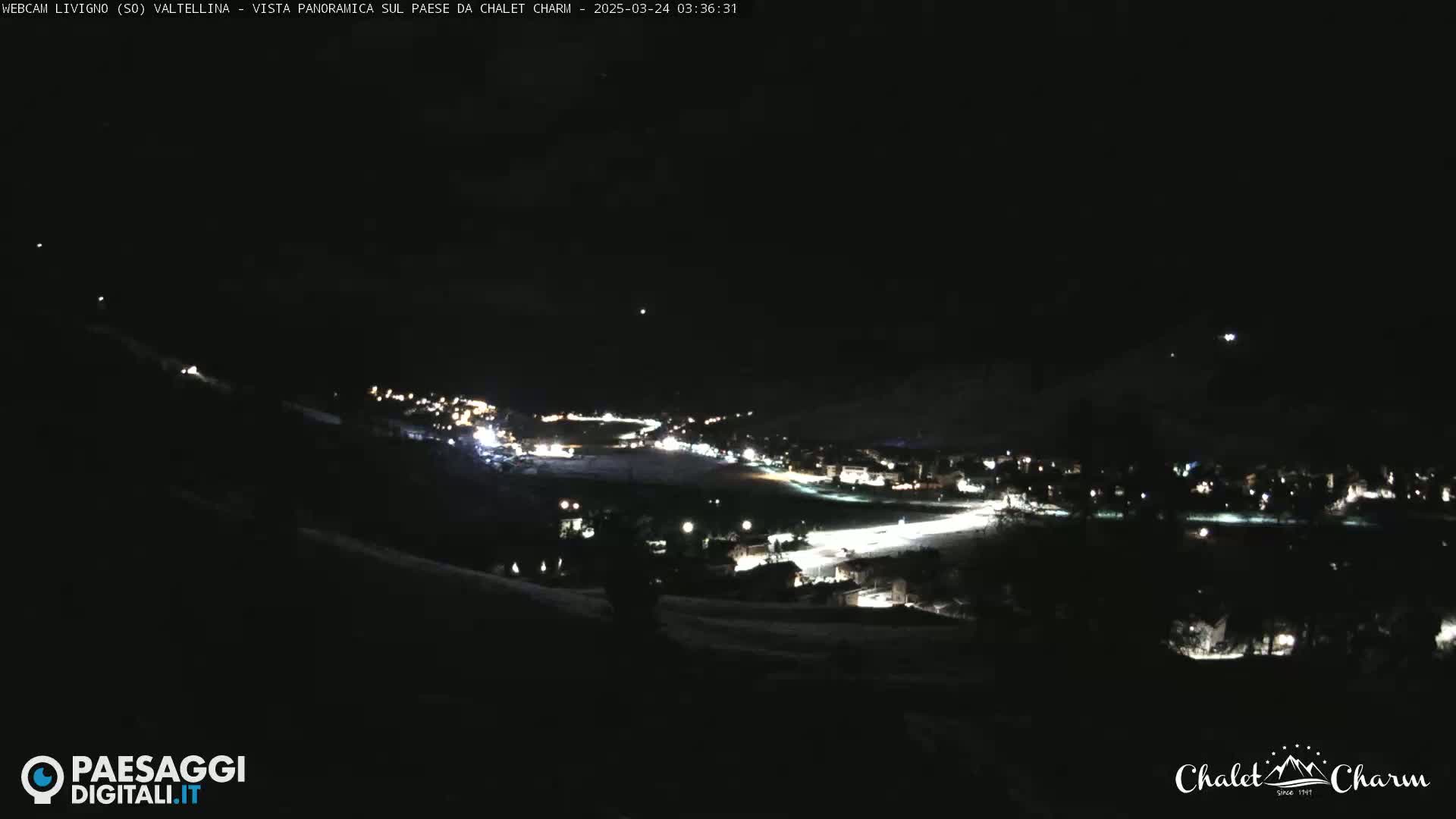 A nighttime, panoramic view of a snow-covered town illuminated by scattered lights.