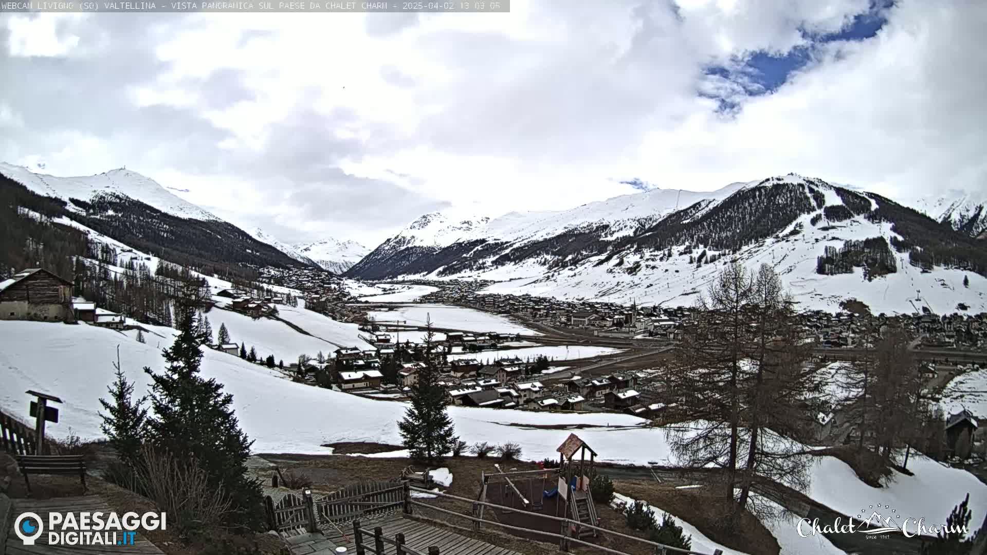 A snow-covered mountain village nestled in a valley under a cloudy sky.