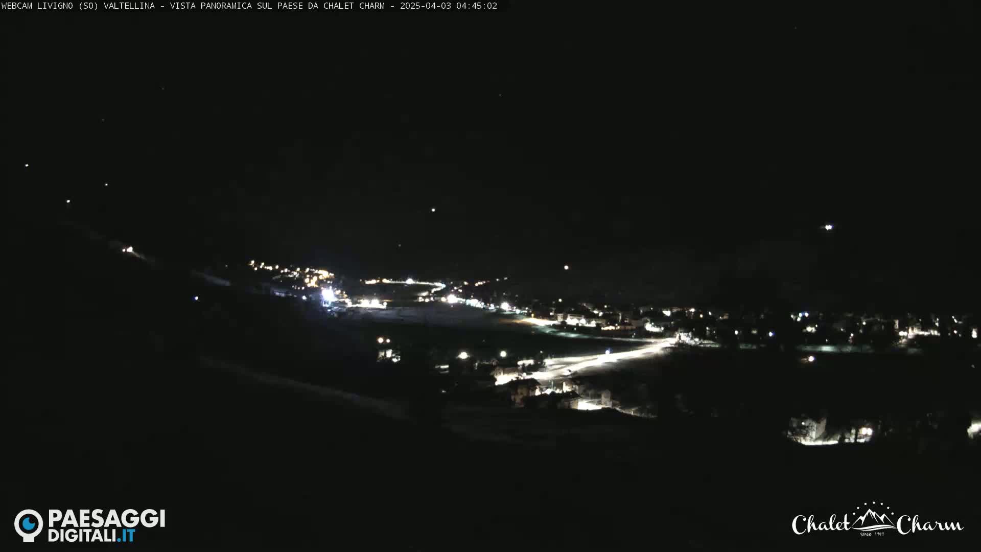 A nighttime, panoramic view of a town illuminated by scattered lights under a clear, dark sky.