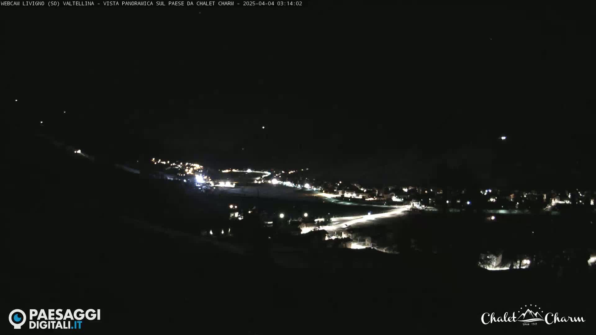 A nighttime, panoramic view of a town illuminated by streetlights under a clear, dark sky.