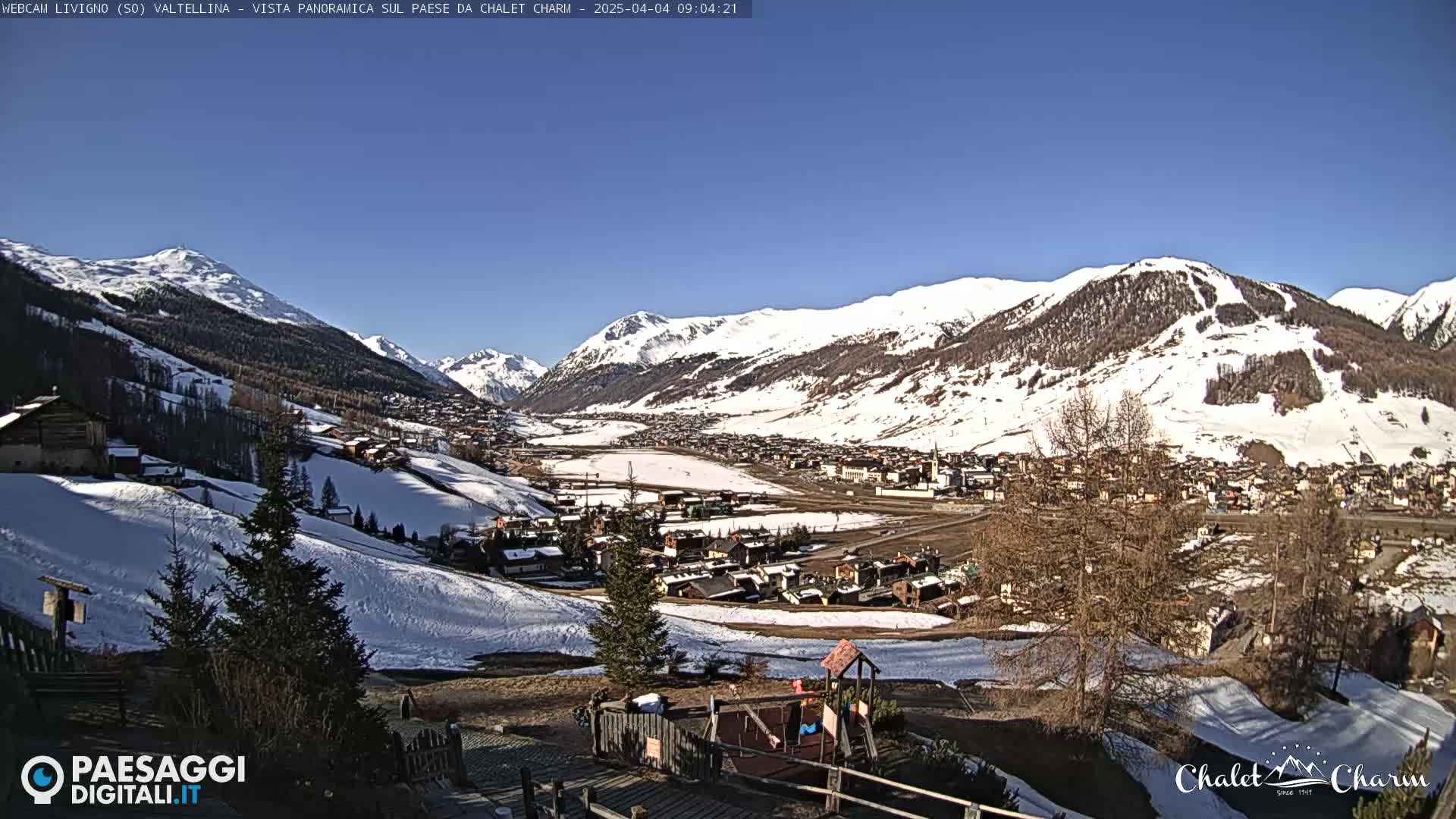 A panoramic view of a snow-covered mountain valley town on a sunny day.