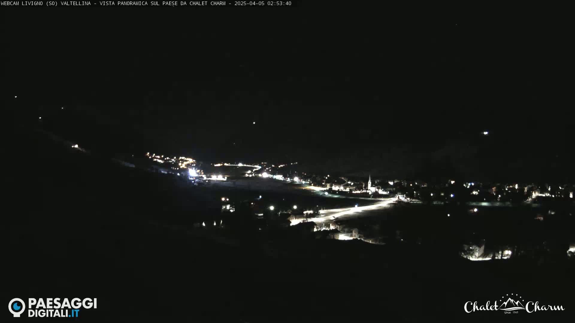 A nighttime, panoramic view of a town's lights scattered across a dark landscape.