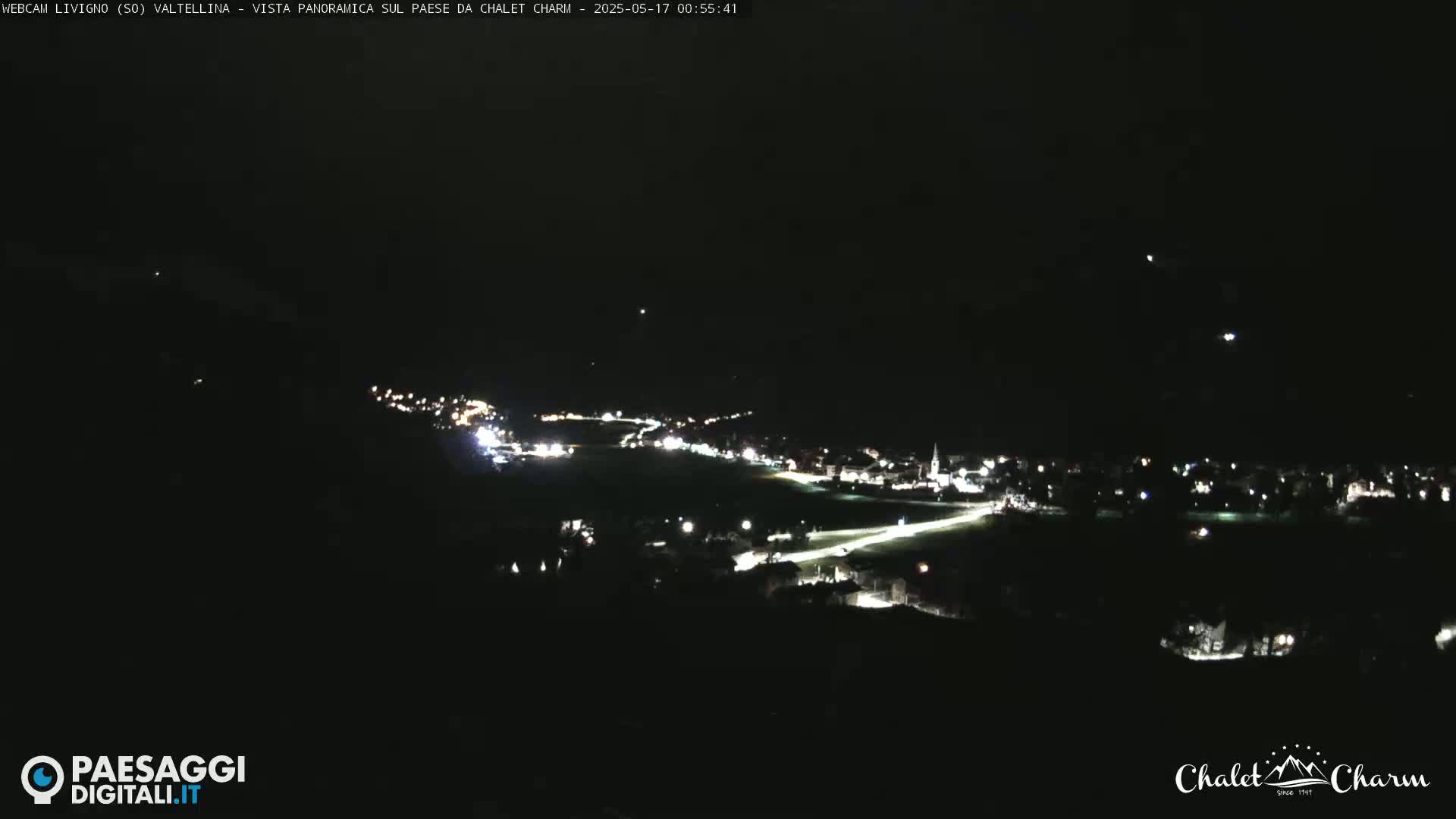 A nighttime, panoramic view of a small town illuminated by scattered lights.