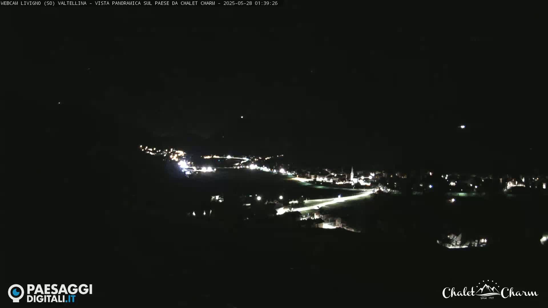 A nighttime long shot shows a small town illuminated by streetlights under a clear, dark sky.